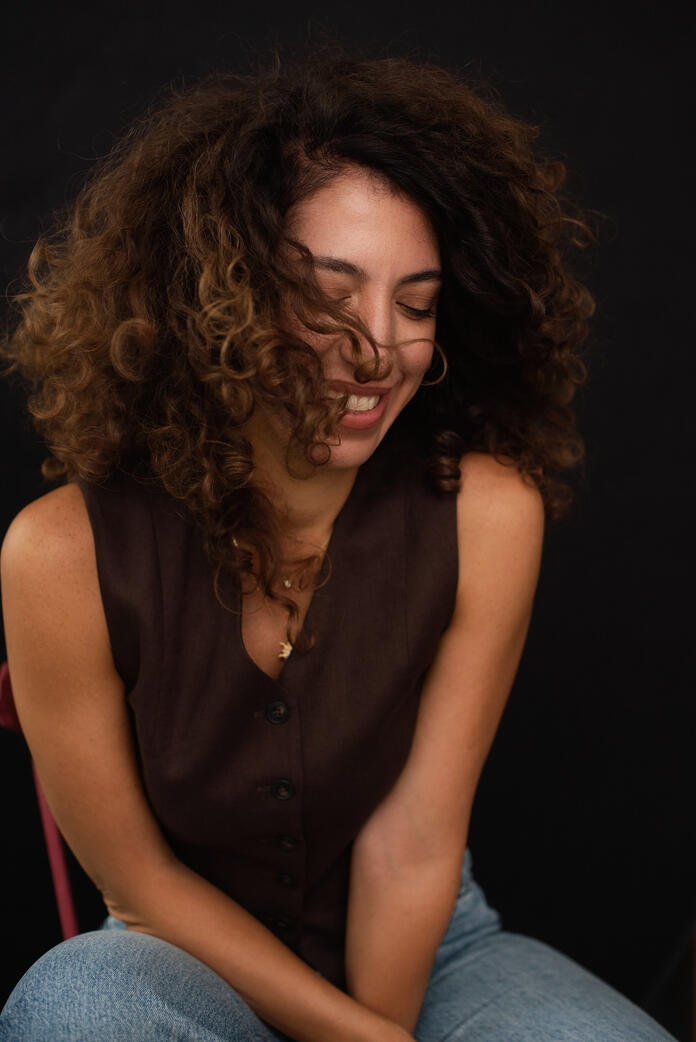 Photo of curly woman, dark background, Berlin studio photoshoot